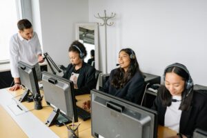 A diverse team of customer service representatives working in an office setting, wearing headsets and using computers.