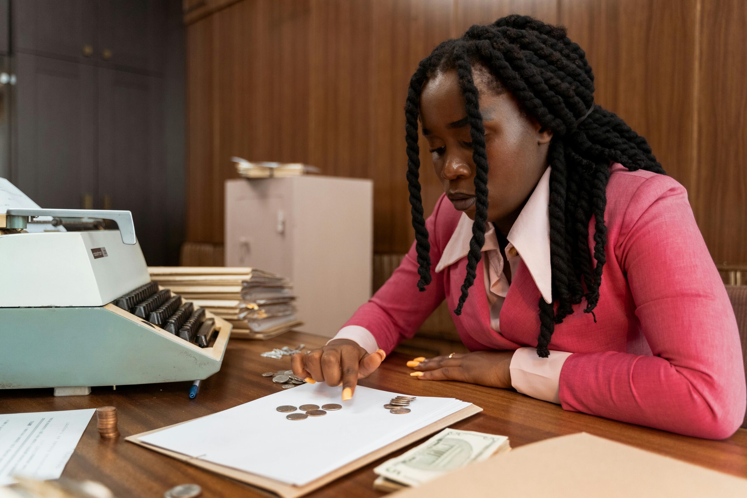 A businesswoman in vintage attire counts coins in a retro office setting.
